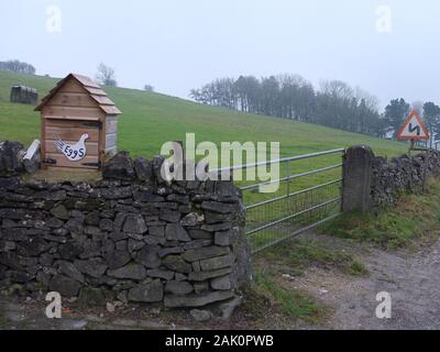 Ehrlichkeit Stall oder Ehrlichkeit, Verkauf Bauernhof Eier von freilaufenden Hühnern eine unbesetzte Holz Stall mit Henne auf einer trockenen Steinmauer in der Derbyshire Peak District Stockfoto