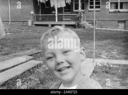 Eine Nahaufnahme schwarz-weiß Bild eines Jungen blonde Junge im Alter von drei in seinem Hinterhof in die Kamera lächeln in Sydney 1963 Stockfoto