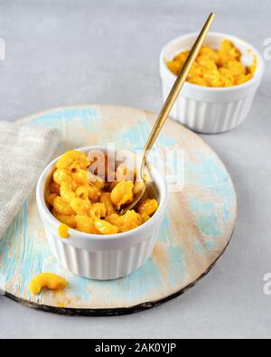 Mac und Käse in zwei Tassen auf hellen Hintergrund. Vertikaler Dampfstoß Stockfoto