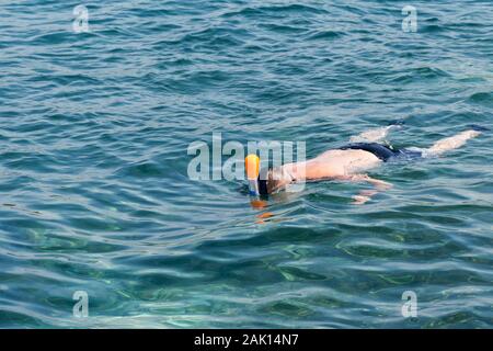 Mann Schwimmen in Blau flaches Meer. Schnorcheln Schnorcheln Full Face Maske. Aktiven Urlaub am Meer. Wasser sport im Meer. Stockfoto