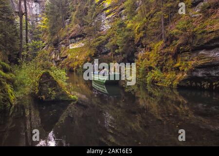 Die Kamnitz-Schlucht - ein Boot mit einem Fährmann und Touristen auf dem Fluss, der durch felsige Schlucht in der Böhmischen Schweiz, Tschechien, fließt Stockfoto