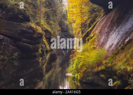 Die Kamnitz-Schlucht - ein Boot mit einem Fährmann und Touristen auf dem Fluss, der durch felsige Schlucht in der Böhmischen Schweiz, Tschechien, fließt Stockfoto