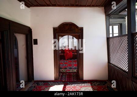 Eine Frau in einem roten Kleid sitzt in einem Raum an der Blagaj Tekija Kloster, in der Nähe von Mostar, Bosnien Stockfoto