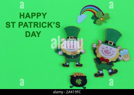 Leprechauns holding Becher Bier neben einem schwarzen Topf voll Gold und einen Regenbogen mit Happy St Patricks Day in grüner Schrift auf grünem Hintergrund Stockfoto