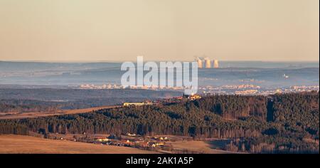 Landschaft - Wald und Hügel mit Kirche im Vordergrund, Stadt im Hintergrund und Atomkraftwerkschornsteine (Temelin, Tschechien) am Horizont Stockfoto