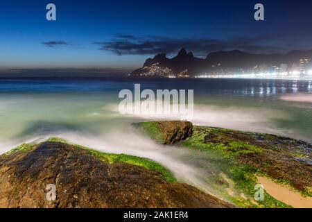 Wunderschöne Aussicht auf Wellen plätschern über Felsen in Ipanema auf die blaue Stunde, Rio de Janeiro, Brasilien Stockfoto