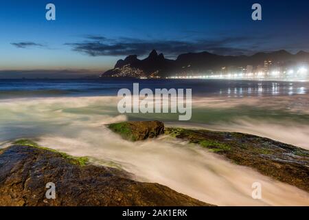 Wunderschöne Aussicht auf Wellen plätschern über Felsen in Ipanema auf die blaue Stunde, Rio de Janeiro, Brasilien Stockfoto