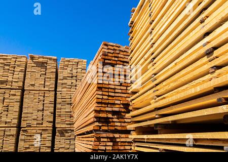 Viele Stapel von behandeltem Kiefernholz sind im Hof von einem Baustoff Lieferant gesehen. Dünne Planken für Holz Rahmen verwendet, stud Wände und Dächer Stockfoto