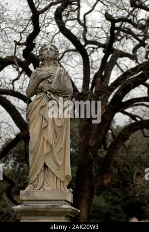 Eine Statue steht vor einem großen Baum auf dem Pioneer Park Cemetery in Dallas, Texas. Der historische Friedhof befindet sich im Stadtzentrum in der Nähe des Pioneer Plaza. Stockfoto