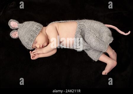 Süßes neugeborenes Mädchen in Maus Kostüm schlafen auf schwarzen Fell