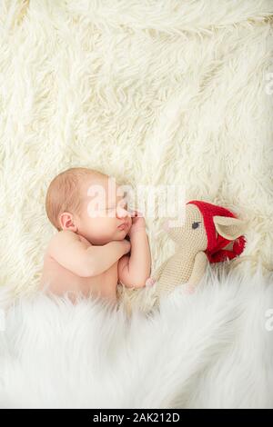 Süßes neugeborenes Mädchen schlafen auf auf weißem Fell Hintergrund closeup Portrait mit Maus Spielzeug Stockfoto