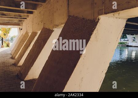 Unter der Brücke. Der Rhythmus der Pfeiler der Brücke verlassen in der Perspektive in der Mitte des weit Punkt. Architektonisches Objekt Stockfoto