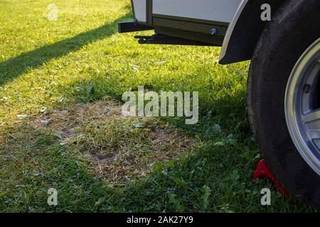 Rasengras durch eine Matte beschädigt und Mangel an Sonnenlicht neben einem Wohnwagen, Wohnmobil Anhänger, Camping, Campingplatz, RV, nachhaltige Praktiken, Leave No Trace Stockfoto