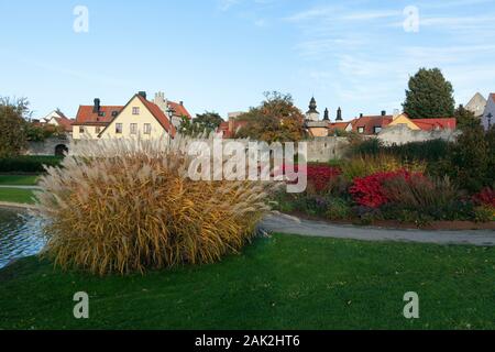 Anzeigen von bunten Sträuchern und Blumen in einem öffentlichen Park. Stadtmauer und alte Gebäude im Hintergrund Stockfoto