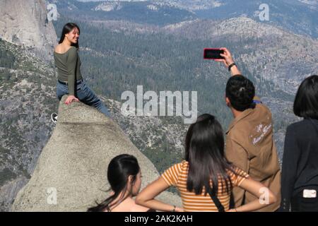 Nahaufnahme der Kletterfrau, die ihr Bild auf einem Felsen am Glacier Point, Yosemite, aufnehmen ließ Stockfoto