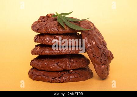 Cannabis Kekse und grünes Blatt. Chocolate Peanut cookies mit Marihuana Öl auf einem gelben Hintergrund. Stockfoto