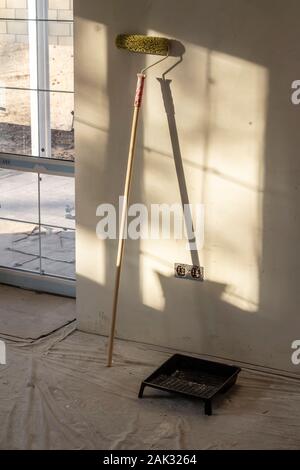 Grüne Farbe Roller steht gegen eine weiße Wand. Stockfoto
