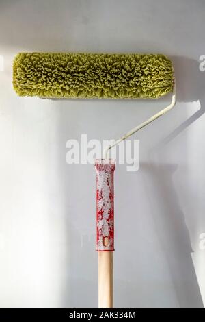 Grüne Farbe Roller steht gegen eine weiße Wand. Stockfoto