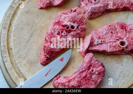 Rohes Schweinefleisch Lunge in Stücke gehackt. Runde alte Schneidebrett. Aufnahme von oben. Soft Focus. Stockfoto