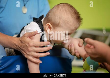 Porträt eines Babys mit zerebraler Lähmung auf Physiotherapie bei Kindern Therapie Zentrum. Jungen mit Behinderung hat die Therapie durch Übungen. Besondere Bedürfnisse. Stockfoto