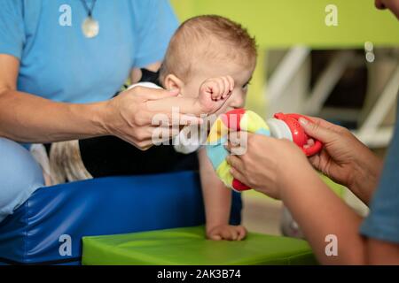 Porträt eines Babys mit zerebraler Lähmung auf Physiotherapie bei Kindern Therapie Zentrum. Jungen mit Behinderung hat die Therapie durch Übungen. Besondere Bedürfnisse. Stockfoto