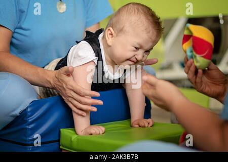 Porträt eines Babys mit zerebraler Lähmung auf Physiotherapie bei Kindern Therapie Zentrum. Jungen mit Behinderung hat die Therapie durch Übungen. Besondere Bedürfnisse. Stockfoto