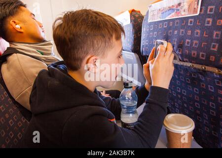 Zehn Jahre alten Jungen auf seinem Telefon, auf einen easyJet Flug nach Wien, London Gatwick Airport, Vereinigtes Königreich. Stockfoto