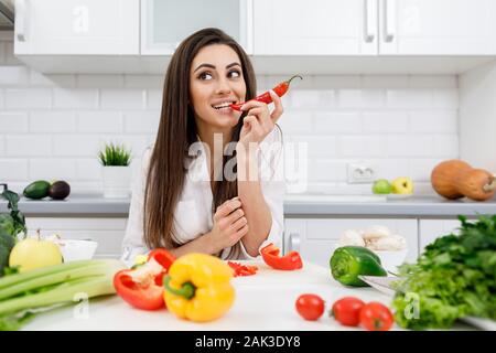 Verspielte süße Brünette Mädchen beißen Chili Tipp Stockfoto