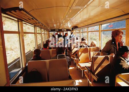 Die Passagiere der Güterwagen der Rack-Eisenbahn Cremallera auf dem Weg zur Bergstation Nuria, Katalonien. Von der Talstation in Ribes de Fres Stockfoto