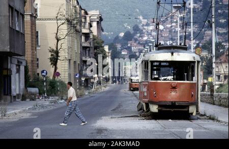 17. August 1993 während der Belagerung von Sarajevo: Der Blick nach Osten entlang Obala Kulina Bana im Stadtzentrum: ruinierte Straßenbahnen stehen entlang einer fast verlassenen Straße aufgegeben. Stockfoto