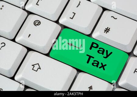 Eine Tastatur mit Pay Tax, die in schwarzer Schrift auf einer grünen ENTER-Taste geschrieben ist. Selbsteinschätzungskonzept für die Zahlung von Steuern. England, Großbritannien, Großbritannien Stockfoto