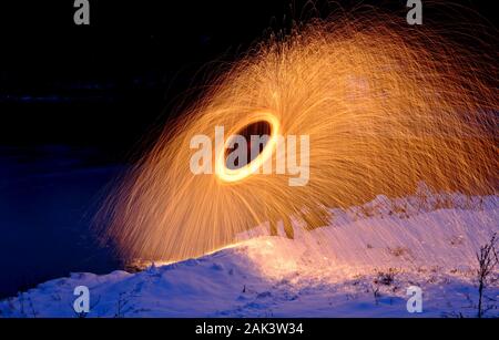 Brennende Stahlwolle Feuerwerk spinning neben einem See Stockfoto