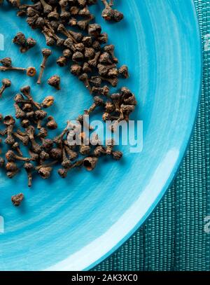 Haufen von roh, getrocknet Zimt blossom buds Gewürz auf blauen Platte Hintergrund mit selektiven Fokus Stockfoto