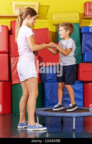Lachendes kind Hopfen auf einem Trampolin in der Turnhalle vom Kindergarten Stockfoto