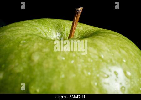 Nahaufnahme von grüner Apfel mit Wassertropfen auf schwarzem Hintergrund Stockfoto
