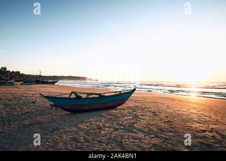 Tropischen Sandstrand mit traditionellen Fischerbooten gegen Meer in wunderschönen Sonnenaufgang, Sri Lanka Stockfoto