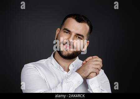 Junge glücklich aussehenden bärtigen Mann anheben Faust auf schwarzen Hintergrund. aufgeregt zum Ausdruck gewinnen Geste Stockfoto