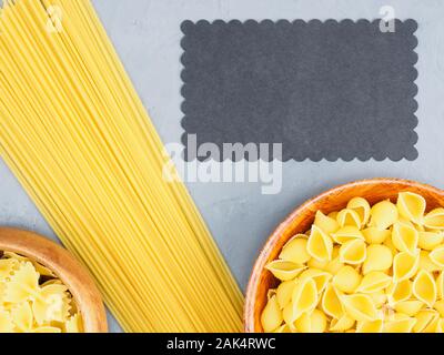 Verschiedene Arten von Nudeln in Holzschalen auf grauem Beton Hintergrund mit schwarzem kopieren. Gesunde Ernährung Konzept Stockfoto