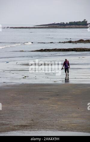 Ein afrikanischer Senior, der am verschmutzten Strand in Conakry, Guinea, Westafrika, spaziert Stockfoto