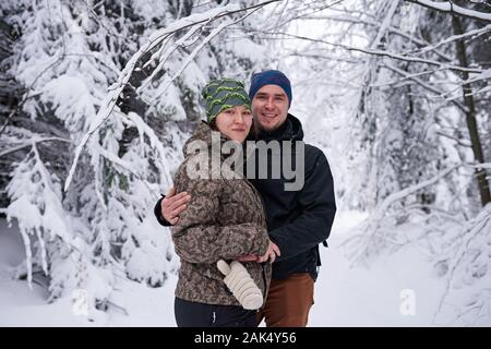 Junges Paar Lächeln beim Wandern in einem verschneiten Wald Stockfoto