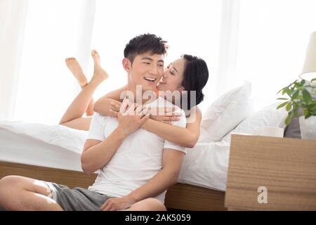 Glückliches junges chinesisches Paar, das ihre Liebe im Schlafzimmer genießt Stockfoto