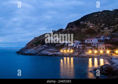 Chiessi Insel Elba, Toskana, Italien. Wunderschöne Aussicht auf das Dorf bei Sonnenuntergang. Macchia, Wohnhäuser mit gelben Lichter und Strand Stockfoto