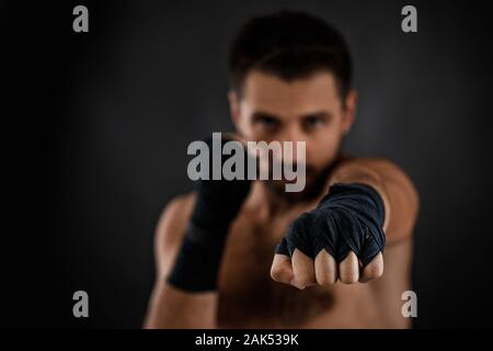 Boxer Mann mit Bandage auf praktische Ausbildung vor dem Kampf und mit den verschiedenen Bewegungen auf schwarzen Hintergrund. Fokus auf Hand Stockfoto