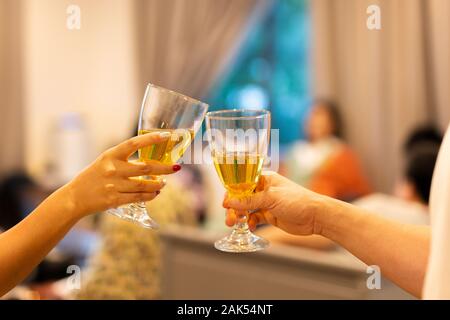 Hand Anstoßen mit weißen Wein zu feiern Feiertag. Stockfoto