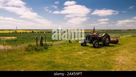 Eine rostige Oldtimer Traktor sitzt auf der Seite einer Rasenfläche in Bilsington in der Landschaft von Kent, England. Stockfoto