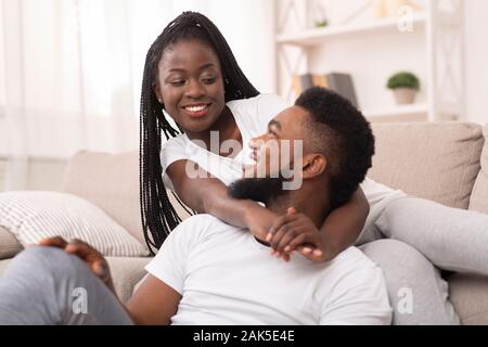 Happy afro Ehegatten zu Hause ausruhen, Kuscheln und Zeit miteinander zu verbringen, einander mit der Liebe Stockfoto