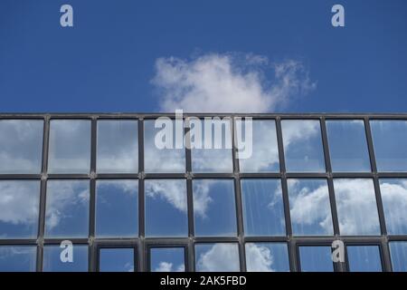 Reflexionen von Wolken und blauer Himmel auf den Aufbau von Windows. Modernen Glasfassade architektonisches Detail. Stockfoto