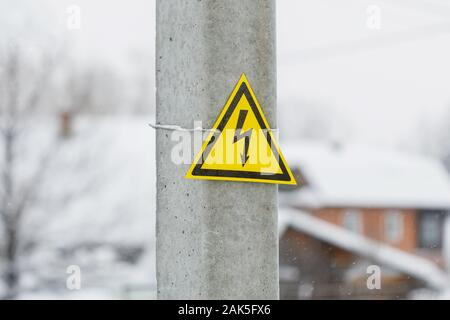 Gefahr Hochspannung Warnschild mit gelben Dreieck und Blitz auf elektrische Pole Stockfoto