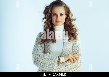 Portrait von eleganten Hausfrau mit langen gewelltes Haar in Pullover und Strickjacke isoliert auf Winter hellblau hinterlegt. Stockfoto