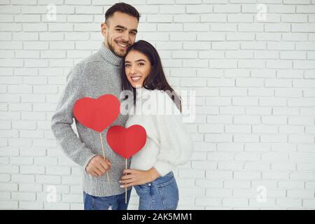 Das Konzert zum Valentinstag. Junges Paar mit Herz in der Hand auf einem weißen Stein Hintergrund. Stockfoto